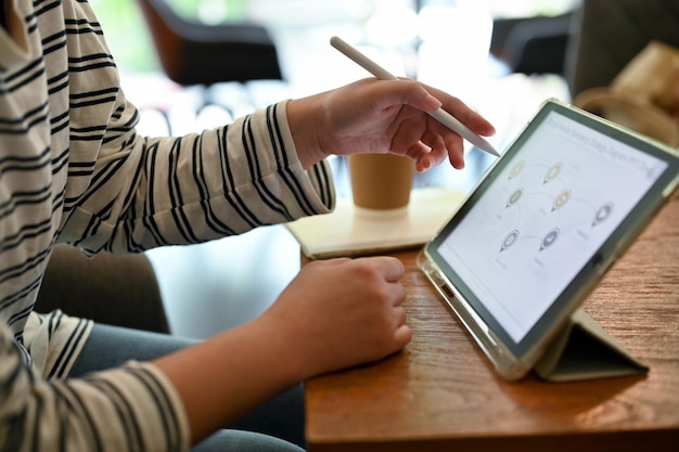 Image recadrée d'une étudiante asiatique faisant ses devoirs sur une tablette numérique