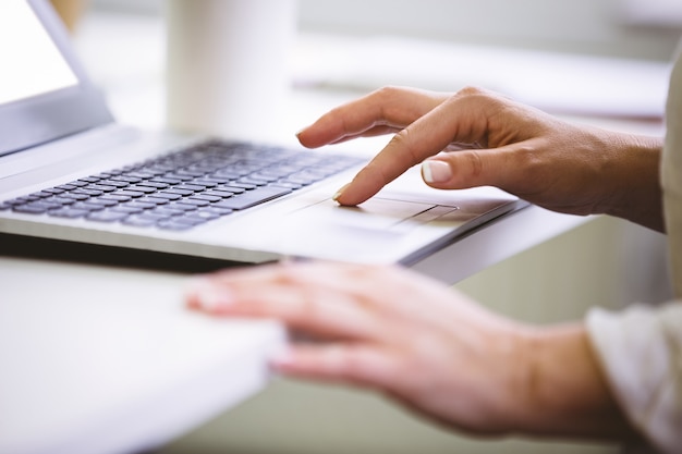 Image recadrée de femme d'affaires à l'aide d'un ordinateur portable au bureau