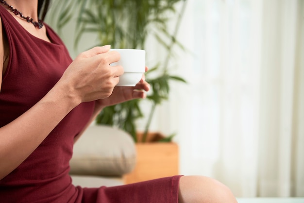 Image recadrée d'une femme d'affaires élégante avec une tasse de café bénéficiant d'un moment calme après avoir terminé le travail