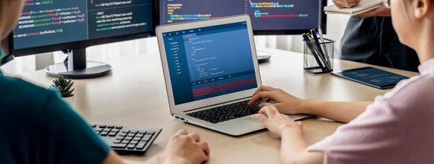 Image recadrée d'une femme développeur web codant sur un ordinateur portable pendant que l'ordinateur affiche le programme et le code logiciel dans un bureau moderne Close Up femme d'affaires main se concentrer sur l'analyse des données en plein essor