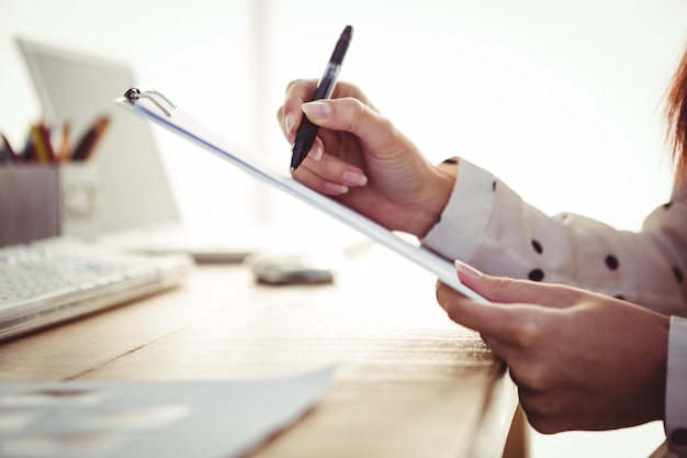 Image recadrée de femme écrivant sur le presse-papiers