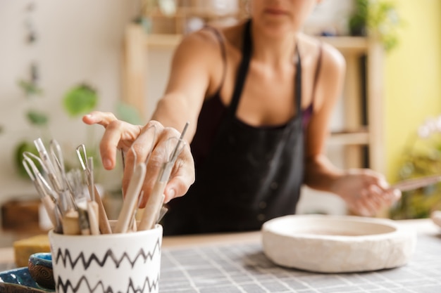 Image recadrée d'une femme faisant de la vaisselle en céramique et poterie à l'atelier