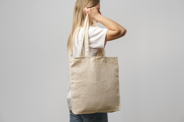 Image recadrée d'une femme tenant un sac à provisions beige en studio
