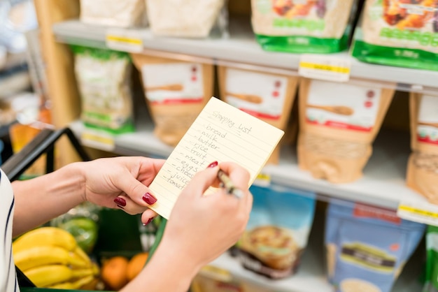 Image recadrée d'une femme vérifiant la liste de courses dans une épicerie