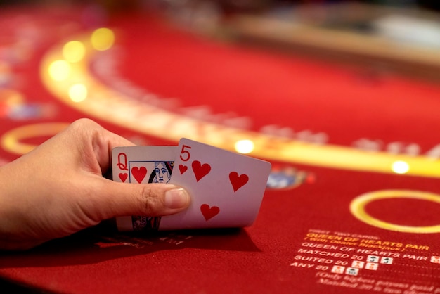 Image recadrée d'une fille jouant au poker à table dans un casino et tenant des cartes à jouer