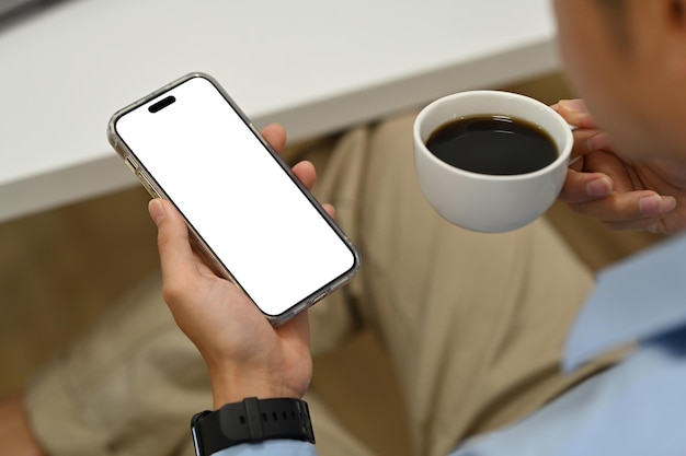 Image recadrée d'un homme buvant du café et utilisant un téléphone intelligent Écran vide pour le texte publicitaire et le montage d'affichage graphique