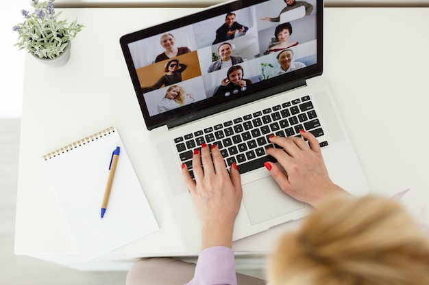 Image recadrée d'une jeune étudiante assistant à une conférence en ligne sur un ordinateur portable au bureau