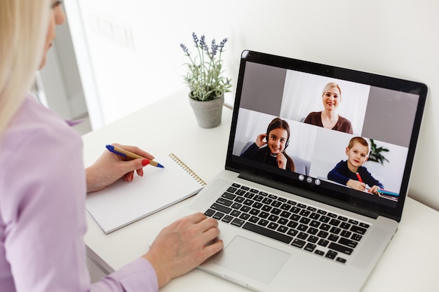 Image recadrée d'une jeune étudiante assistant à une conférence en ligne sur un ordinateur portable au bureau