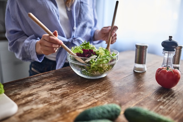 L'image recadrée d'une jeune femme séduisante cuisine dans la cuisine. Faire de la salade. Concept de mode de vie sain.