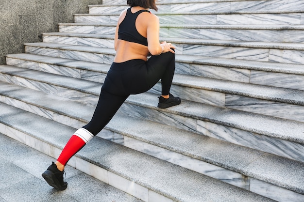 Image recadrée d'une jeune femme sportive faisant des exercices d'étirement à l'extérieur