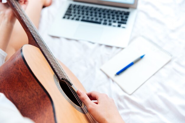 Image recadrée d'une main féminine jouant de la guitare