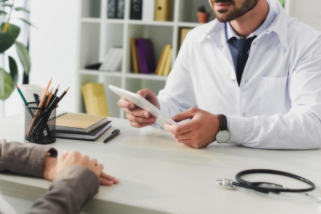 Image recadrée d'un médecin tenant une tablette dans une clinique