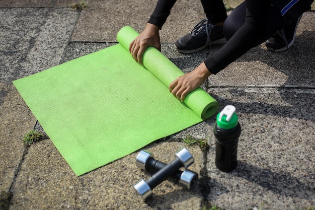 Image recadrée d'une personne roulant un tapis de yoga