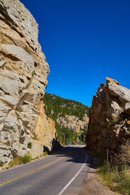 Image de la route coupant à travers de gros rochers en montagne contre le ciel bleu à la verticale