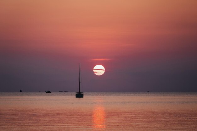 Image de silhouette d'un beau coucher de soleil sur la mer avec voilier