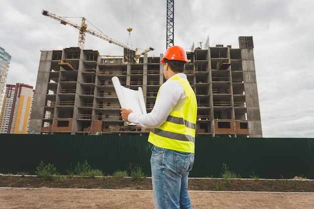 Image tonique de l'ingénieur en casque et gilet inspectant le chantier