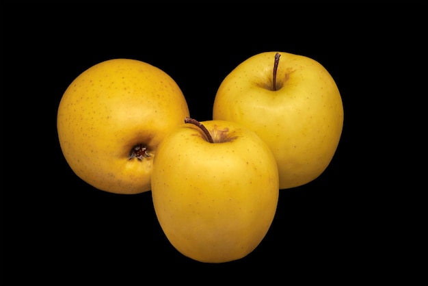 Image de trois pommes jaunes mûres sur fond noir