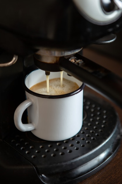 Image de verser le café de la machine à café dans la tasse dans la cuisine