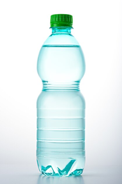 Image verticale de bouteille propre en plastique avec couvercle vert rempli d'eau sur fond blanc