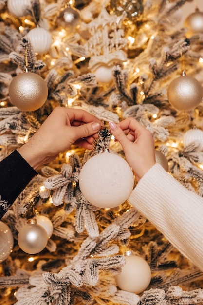 Image verticale charmant jeune couple romantique décorant le sapin de Noël s'embrassant embrassant la maison