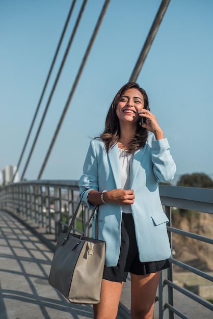 Image verticale d'une femme d'affaires hispanique heureuse au téléphone