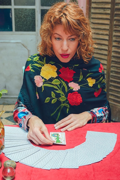 image verticale d'une femme lecteur de tarot assise pensant et lisant des cartes