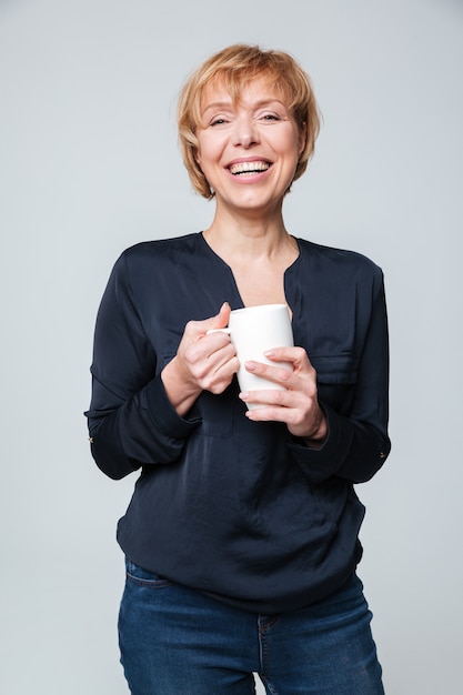 Image verticale de rire femme âgée tenant la tasse de thé