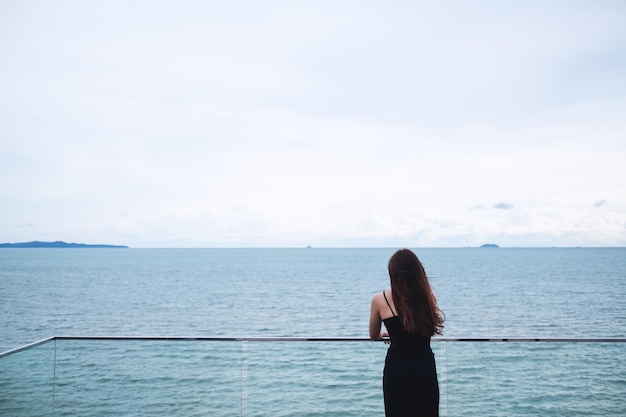 Image vue arrière d'une jeune femme debout et regardant la mer et le ciel bleu