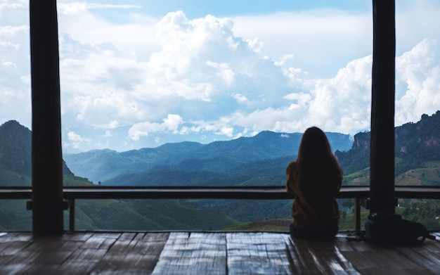 Image vue arrière d'une voyageuse assise et regardant une belle vue sur la montagne et la nature