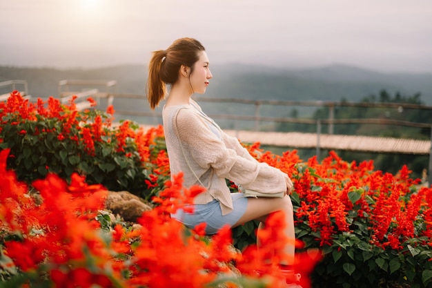 Image de la vue arrière d'une voyageuse assise et regardant un magnifique champ de fleurs de montagne et une vue sur la naturexA