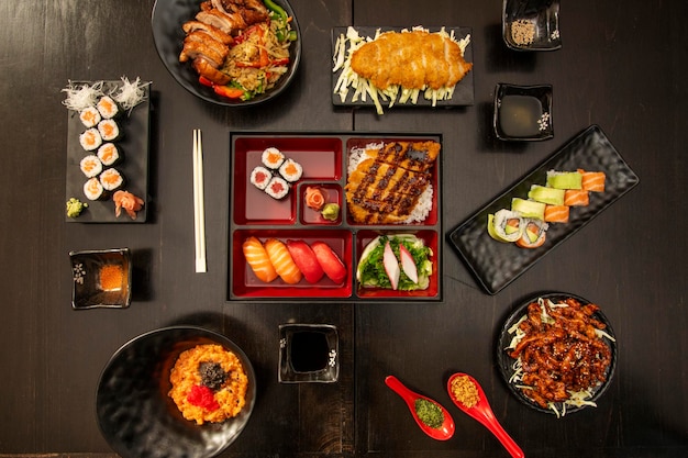 Photo image vue de dessus de la cuisine asiatique et des sushis saumon makis canard rôti poulet pané frit uramakis de saumon lanières de boeuf caramélisées sauce soja œufs de poisson assortiment de nigiri