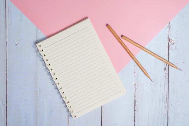 Image vue de dessus du cahier avec des crayons sur une table en bois avec un fond rose