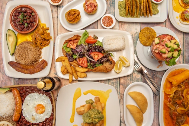 Image vue de dessus d'un ensemble de plats colombiens avec valluna escalope empanadas paisa plateau cocktail de crevettes patacones frites viande râpée et guacamole