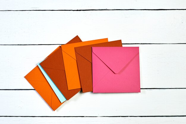 Image d'une vue de dessus d'enveloppes multicolores sur une table en bois blanc.