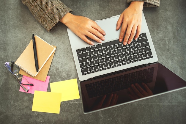 Image vue de dessus d'une femme d'affaires utilisant et tapant sur un ordinateur portable avec des documents sur la table au bureau