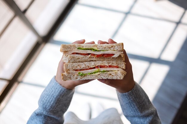 Image vue de dessus d'une femme tenant et mangeant un sandwich de blé entier le matin