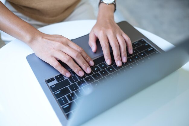 Image vue de dessus d'une femme travaillant et tapant sur le clavier d'un ordinateur portable sur la table