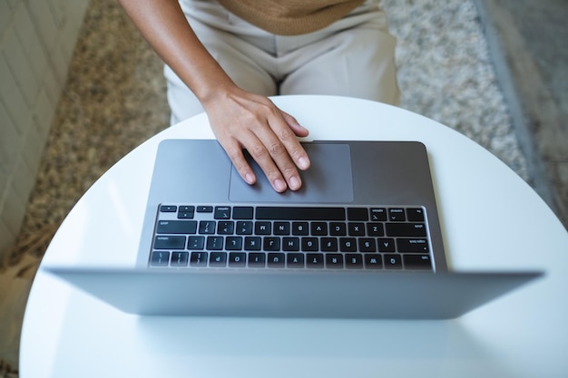 Image vue de dessus d'une femme travaillant et touchant sur le pavé tactile d'un ordinateur portable sur la table