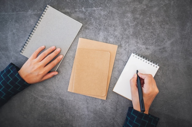 Image vue de dessus d'une main tenant un stylo et allant écrire sur un cahier blanc vierge