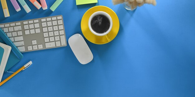 L'image Vue De Dessus D'une Tasse De Café Met En Place Un Bureau De Travail Coloré Entouré D'équipements De Bureau.