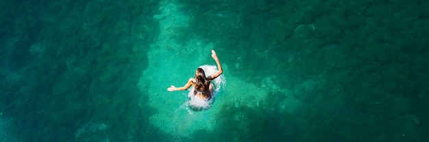 Image vue large d'une jeune femme sautant dans un beau lac vert froid.