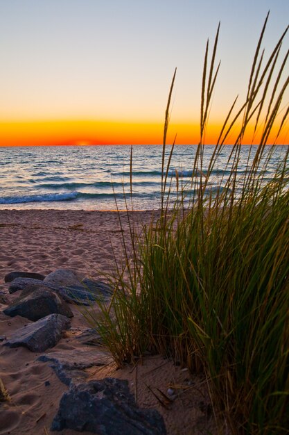 Image d'une vue paisible sur les roseaux des dunes de sable donnant sur un lac au coucher du soleil