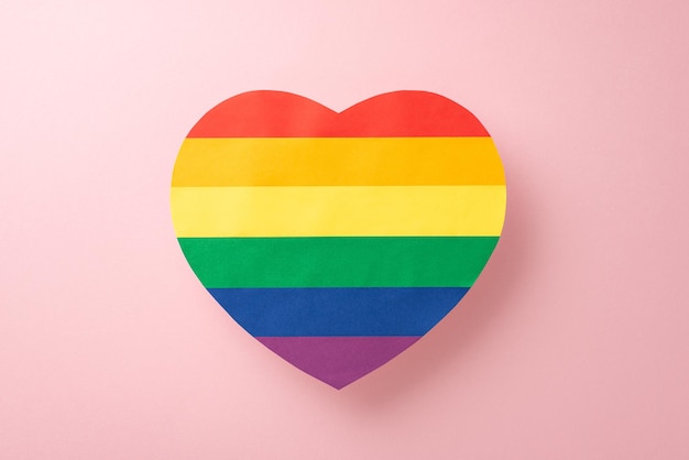 Une image en vue supérieure du symbole de soutien LGBT grand cœur de couleur arc-en-ciel affiché sur un fond rose pastel avec un espace ouvert pour le texte ou la publicité