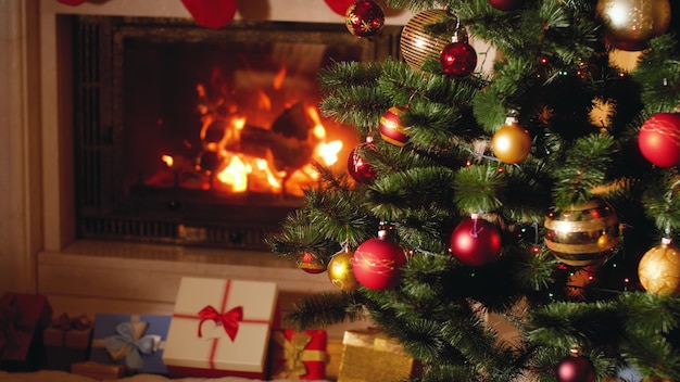 Images 4k de gros tas de cadeaux et de cadeaux à côté d'une cheminée en feu et d'un sapin de Noël rougeoyant dans le salon la veille de Noël