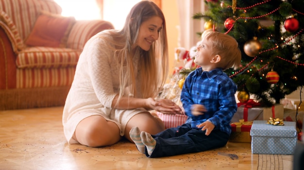 Images 4k d'un petit garçon heureux avec une jeune mère jouant et jetant des confettis colorés et des paillettes. Famille s'amusant et s'amusant pendant les vacances d'hiver et les célébrations.