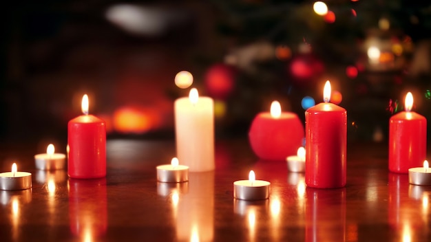 Images de chariot 4k de beaucoup de bougies rouges et blanches allumées sur une table en bois contre un arbre de Noël