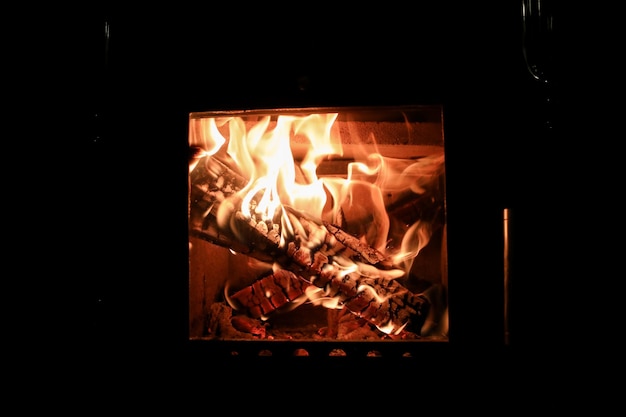 Des images d'une flamme dansante de couleurs vives dans la cheminée en gros plan du bois de chauffage brûlant confortable et chaud
