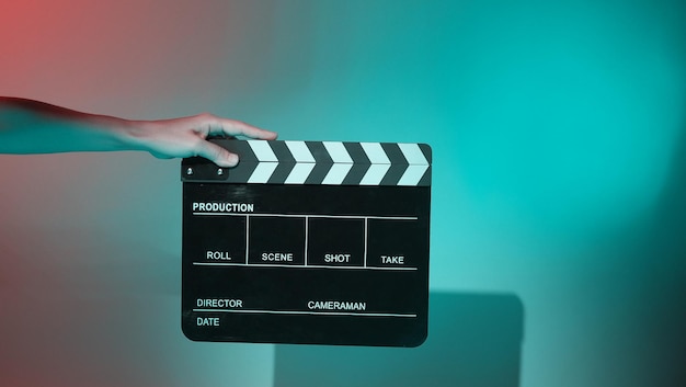 Images floues d'ardoise de film ou de panneau de clapet. La main tient le clap de fabrication de film vide sur fond de couleur en studio pour le tournage ou l'enregistrement de films. Ardoise de film pour la production vidéo Youtuber.