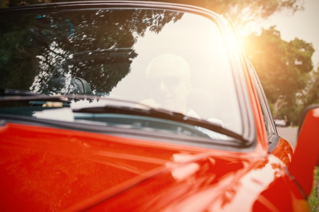 Images d'un homme conduisant une voiture rouge