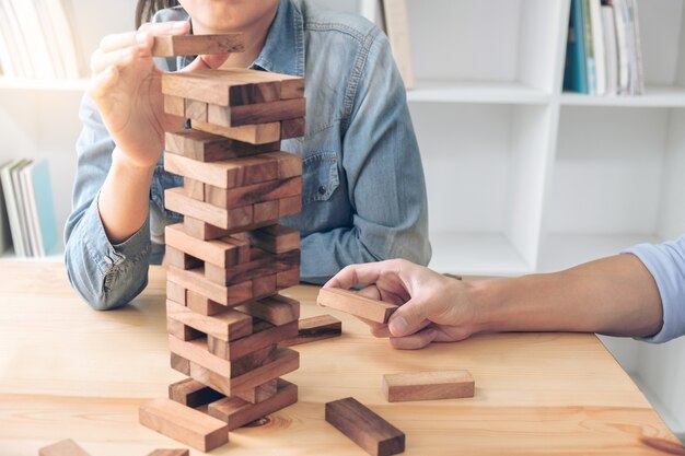 Images de la main des gens d&#39;affaires plaçant et tirant le bloc de bois sur la tour